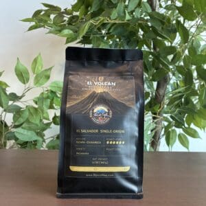 Coffee bag on wooden table, leafy background.