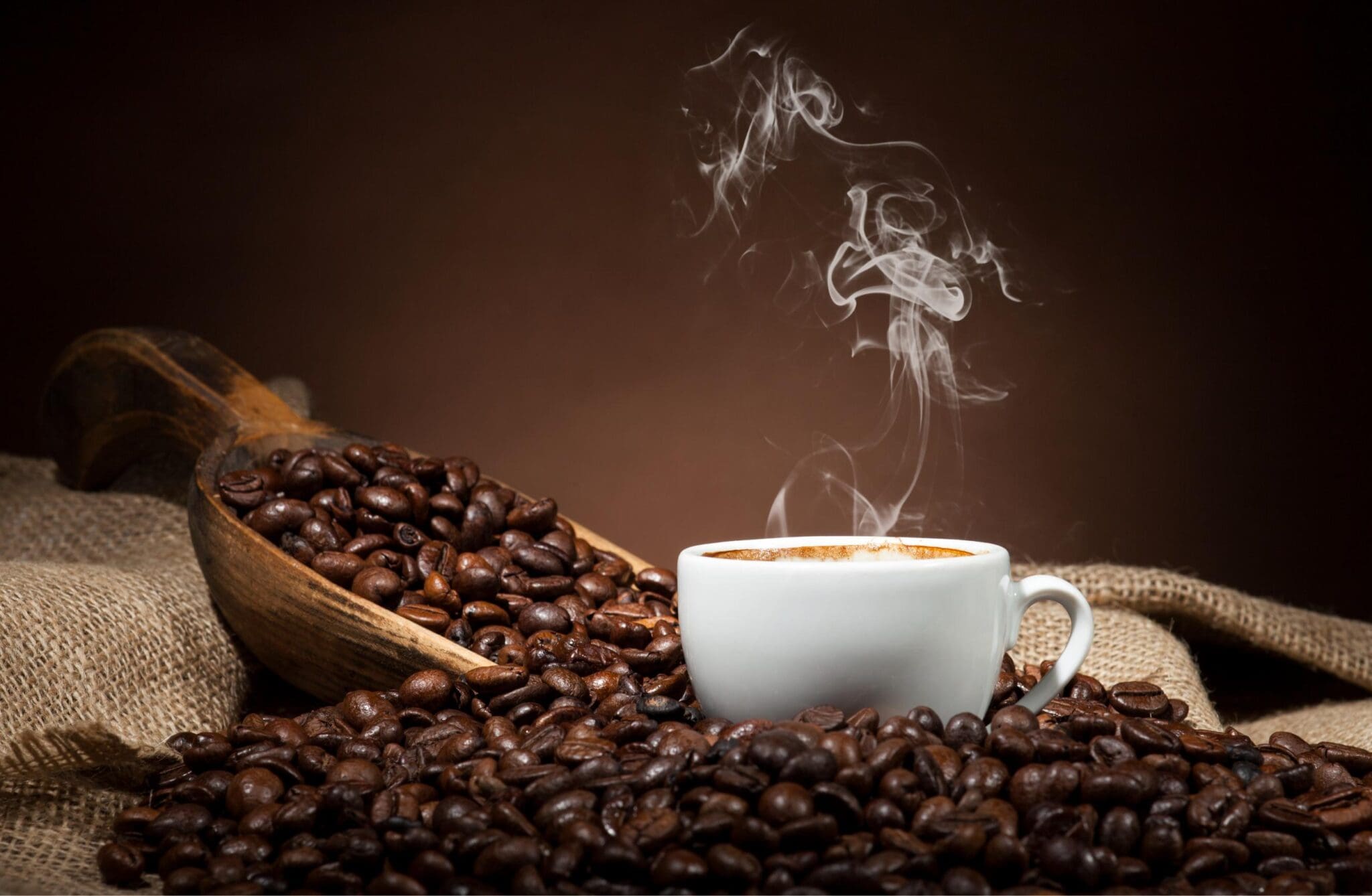 Steaming coffee cup surrounded by coffee beans.